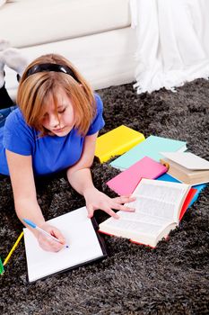 teenager girl sitting on the floor with lot of books and doing homework learning reading