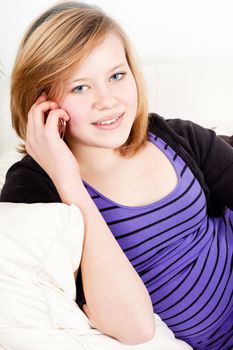 teenager girl smiling and lying on couch with mobile phone and talking