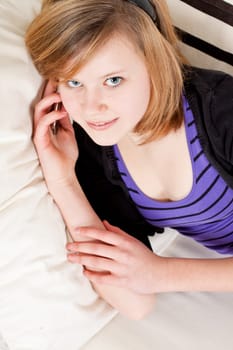 teenager girl smiling and lying on couch with mobile phone and talking