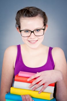 Silly smiling schoolgirl with glasses and lots of books having fun