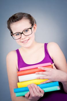 Silly smiling schoolgirl with glasses and lots of books having fun