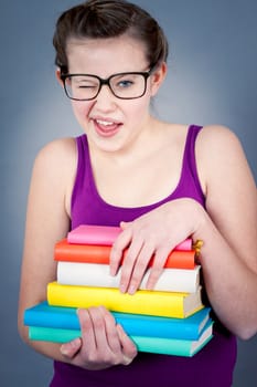 Silly smiling schoolgirl with glasses and lots of books having fun