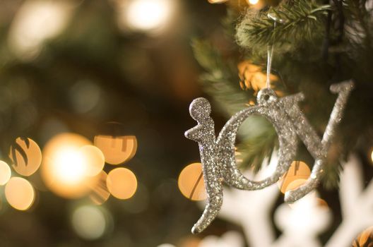 sparkling silver joy ornament hanging on a Christmas tree for the holidays