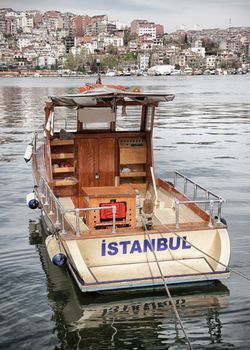 Postcard from Istanbul. Motor boat by the Golden Horn - Istanbul, Turkey. The Beyoglu district in the background.