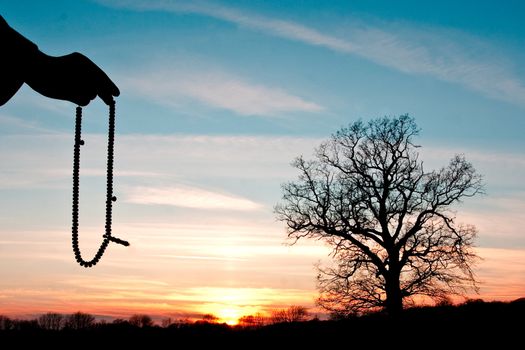 hand holding beads against a sunset scene