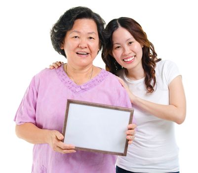 Asian parent and adult offspring holding a blank board smiling, isolated on white background