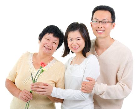 Asian adult offsprings giving carnation flower to senior parent on mother's day.