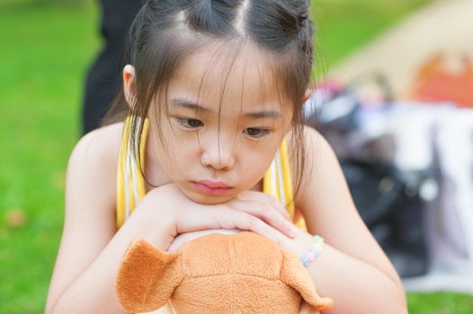 Outdoor upset Asian child. Little girl showing her unhappy face.