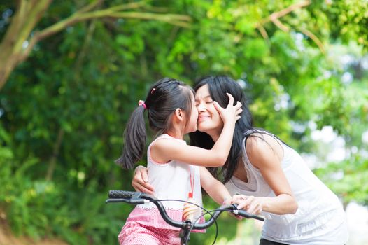Asian child kissing her mother. Asian family having fun outdoor, biking outdoor.
