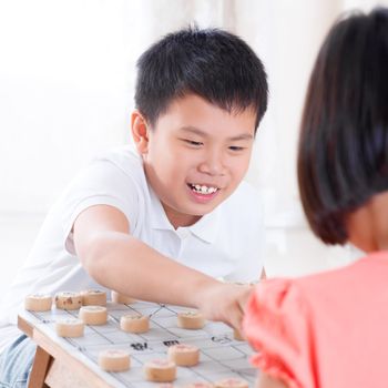 Asian children playing Chinese chess at home.