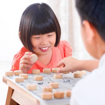 Asian family at home. Asian children playing Chinese chess at home.