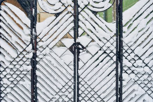 Cast iron gate in Art Nouveau style in snow