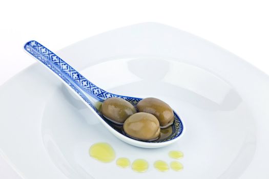 Olives on  spoon and olive oil isolated on white.