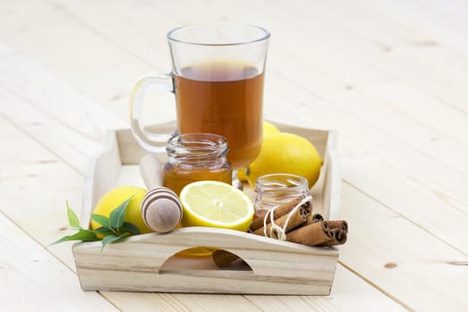 glass of tea, honey, fresh lemons and cinnamon sticks