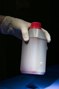 Hand covered in white glove holding white container