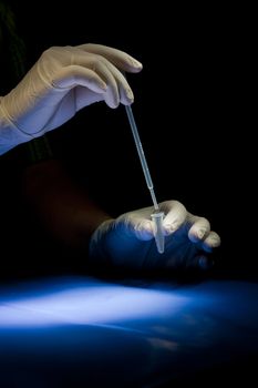 Hands in white gloves hold pipette and tube