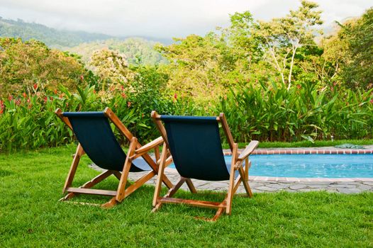 Blue canvas pool chairs overlooking a beautiful tropical landscape in Costa Rica.