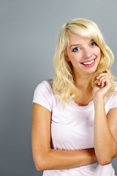Portrait of smiling young blonde caucasian woman on grey background