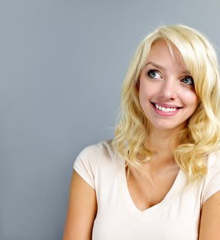 Smiling blonde caucasian woman looking up on grey background