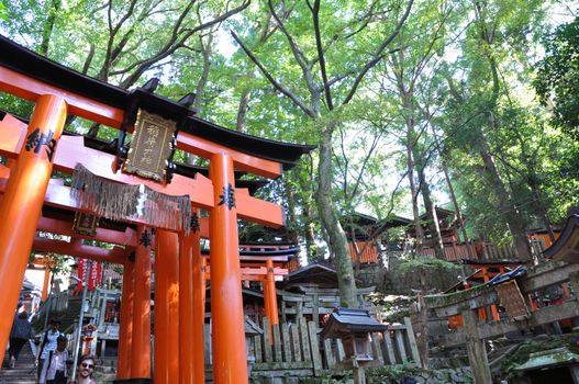 KYOTO, JAPAN - OCT 23 2012: A tourist at Fushimi Inari Shrine on October 23 2012. The shrine is famous for its torii gates walkway that lead to the top of the mountain.