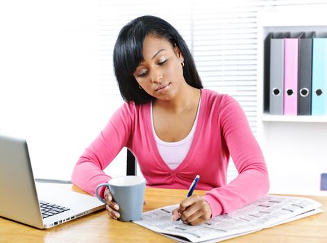 Young black female student looking in newspaper for job