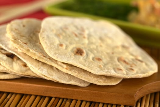 Indian flatbread called chapati on wooden board (Selective Focus, Focus on the front of the first three chapatis)