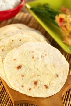 Indian flatbread called chapati on wooden board (Selective Focus, Focus on the big brown spot on the left)