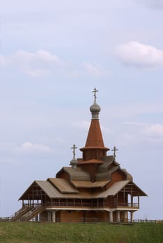 Small wooden church over blue sky with clouds