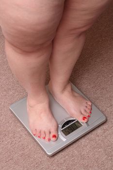 women legs with overweight standing on bathroom scales