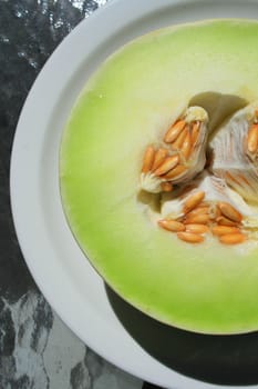 Close up of a honeydew melon on a plate.
