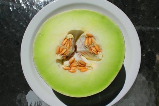 Close up of a honeydew melon on a plate.
