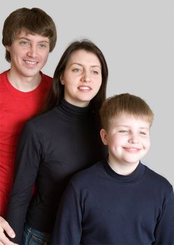 Smiling family on a grey background.
