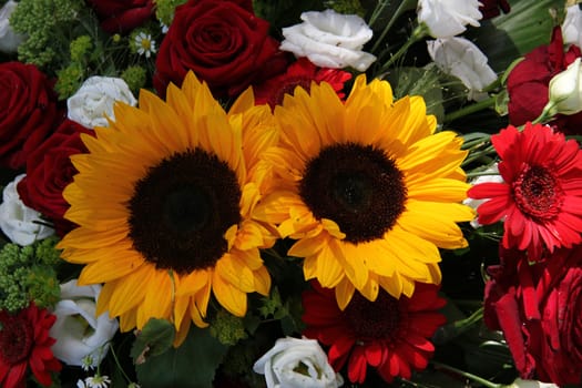 Bright yellow sunflowers and big red roses in a floral arrangement