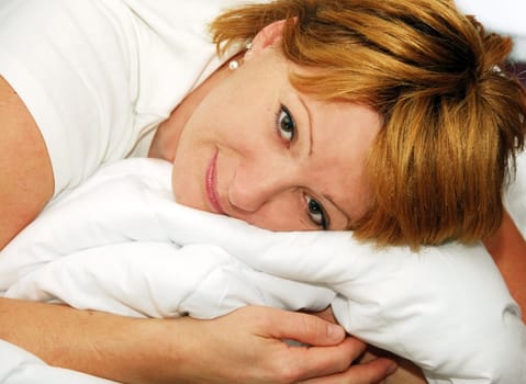 happy smiling caucasian woman portrait with duvet indoors