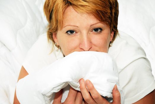 happy caucasian woman in white clean bedding portrait