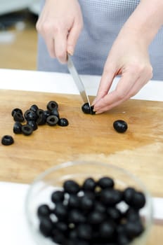 Woman's hands cutting olives