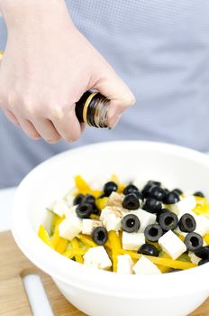 Greek salad preperation: vinegar pours on greek salad