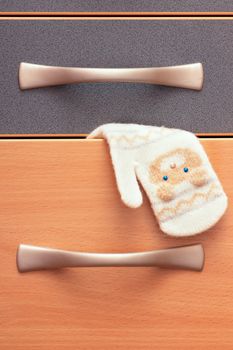 A mitten hanging out of a cupboard