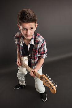 Photo of a teenage male playing a white electric guitar. Taken with wide-angle lens.