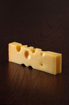 Photo of a block of Emmentaler cheese from Switzerland on a dark wood table.