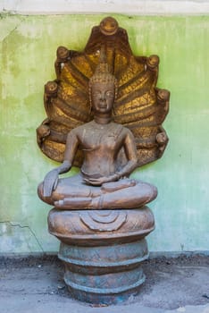 Forgotten smiling Naga head covered Buddha image (Nak Prok Image) at Paa Jareon Tham temple, Chiangmai, Thailand