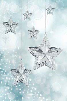 Hanging silver Christmas star ornaments against a festive blue background. 
