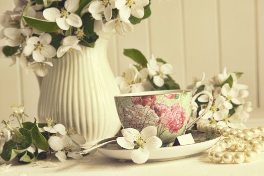 Tea cup with fresh apple blossoms on table