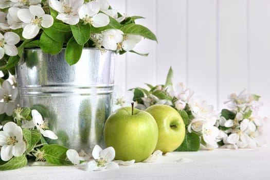 Green apples with blossoms on wooden table