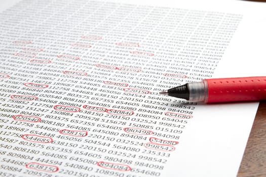 Red pen sitting on a piece of paper with numbers circled. Paper looks as though it is a report with important numbers