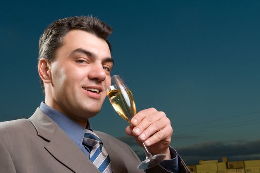 man in a suit against the evening sky with a glass of champagne