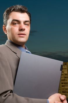 man in a suit against the evening sky with laptop