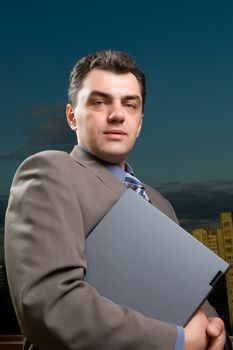 man in a suit against the evening sky with laptop