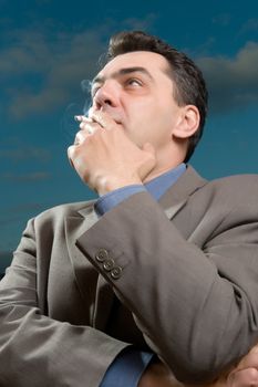 man in a suit against the evening sky smokes