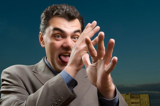 man in a suit against the evening sky shows tongue